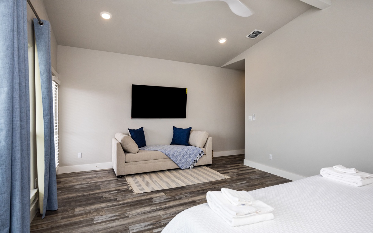 Unwind in your spacious bedroom with plush seating, wall-mounted TV, and fresh linens waiting for your arrival.