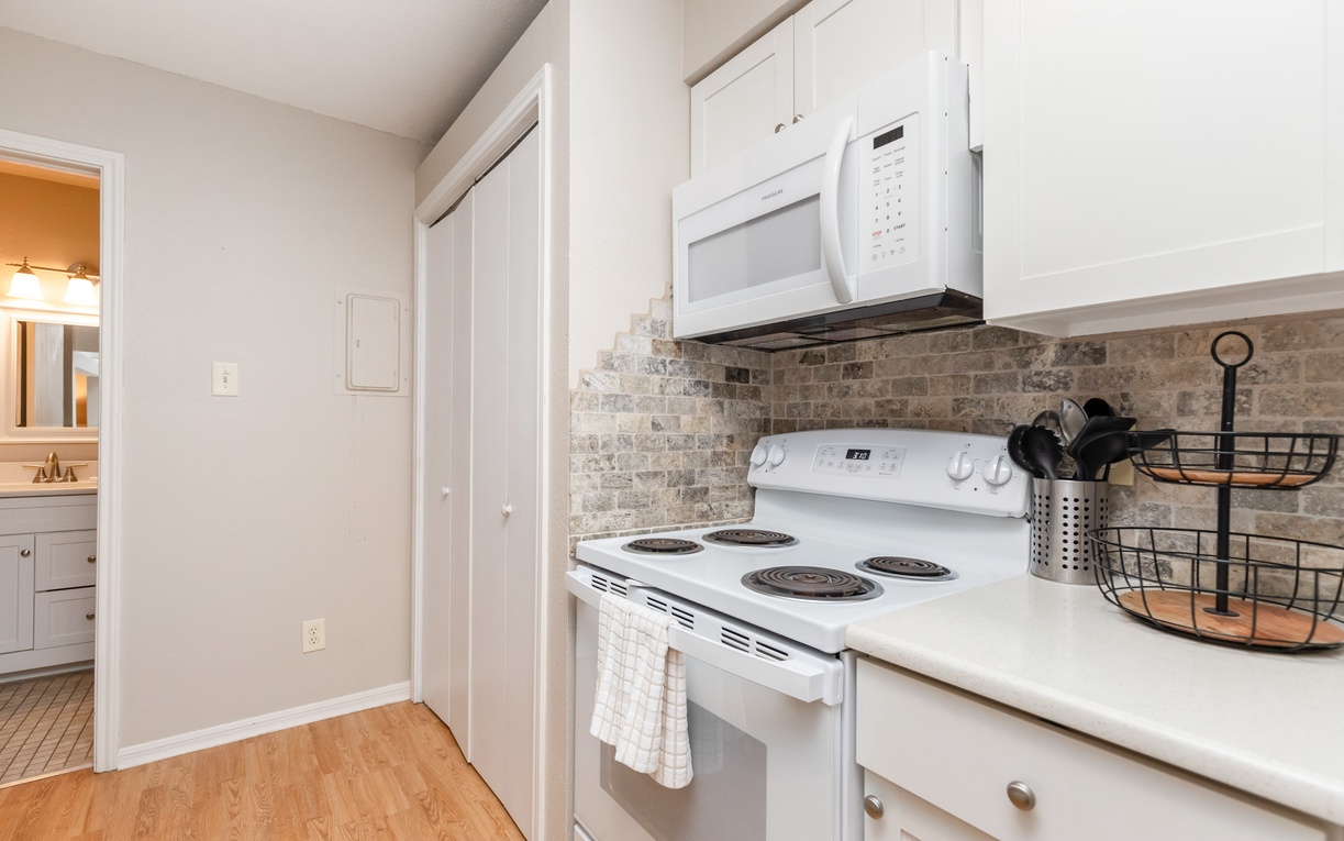 Your fully equipped kitchen awaits with crisp white cabinets, stone-tile backsplash, and modern appliances for easy meal preparation.