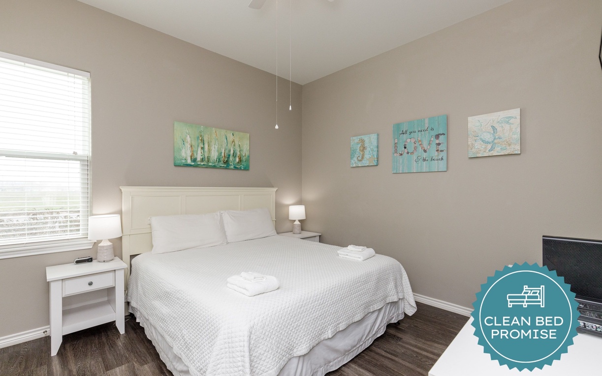 Drift off in your coastal-themed bedroom with crisp linens, beach artwork, and natural light streaming through the window.
