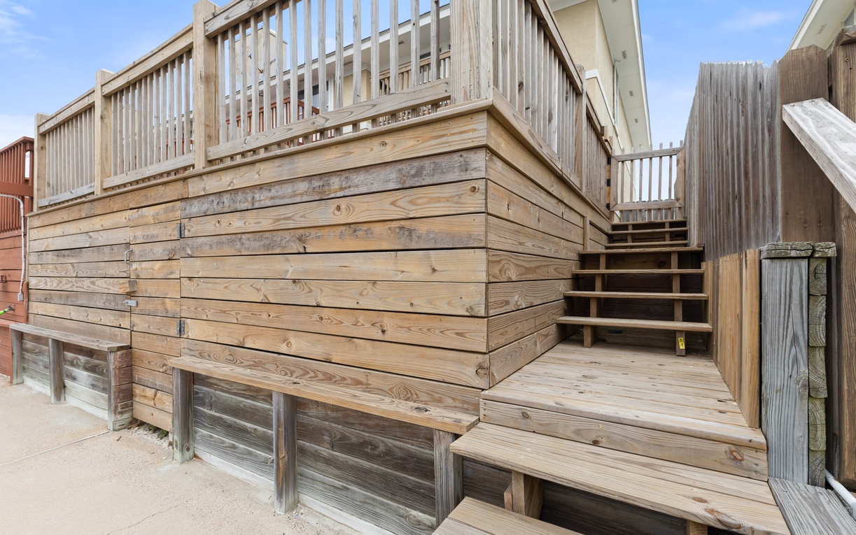 Beachfront property features multi-level wooden decking with stairs connecting different outdoor areas and guest levels.