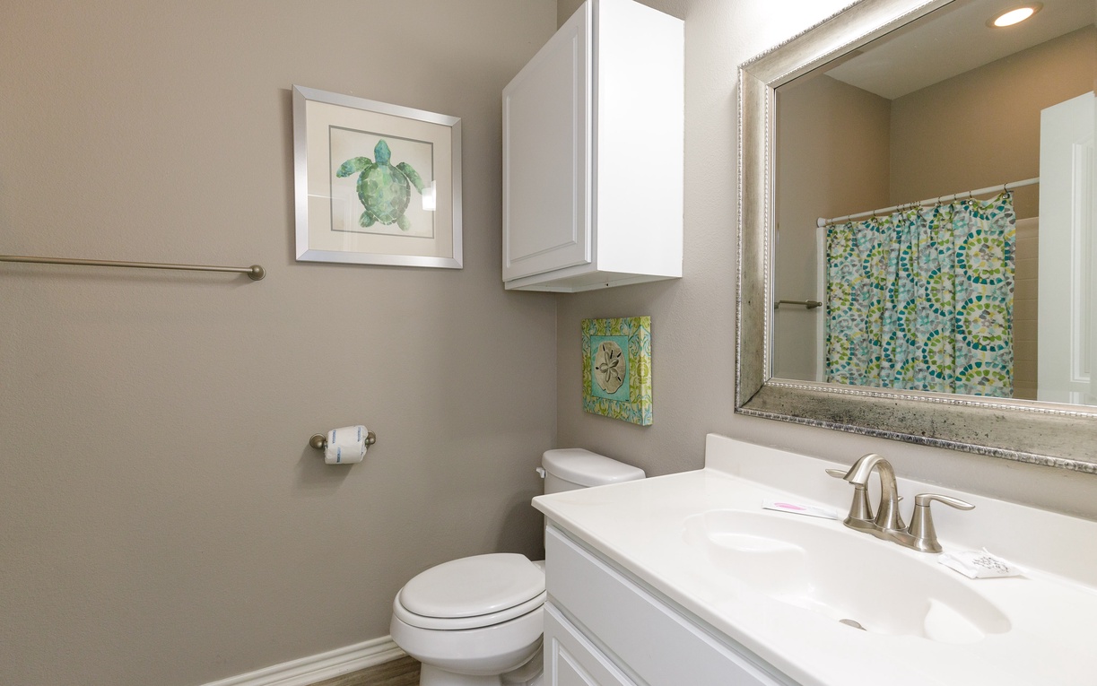 Refresh in your private bathroom featuring coastal artwork and crisp white cabinetry for a clean, relaxing experience.