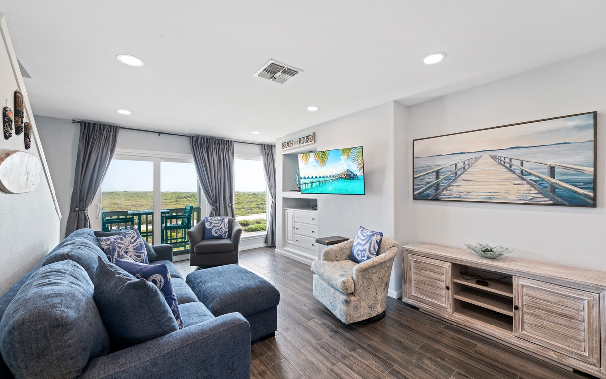 Unwind in your coastal living space with plush seating, a balcony overlooking natural scenery, and calming beach-inspired décor throughout.
