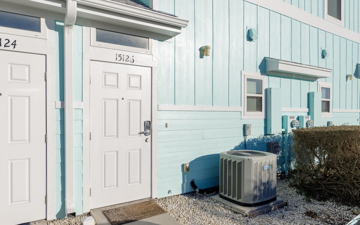Coastal property entrance featuring air conditioning system for your comfort during warm beach days.