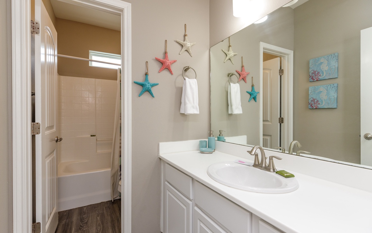Refresh in your coastal-themed bathroom with starfish decor, crisp white linens, and ocean-inspired artwork creating a serene seaside escape.