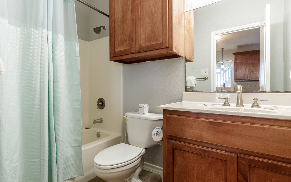 Refresh in your private bathroom featuring warm wood cabinetry, a relaxing tub-shower combo, and thoughtful amenities.