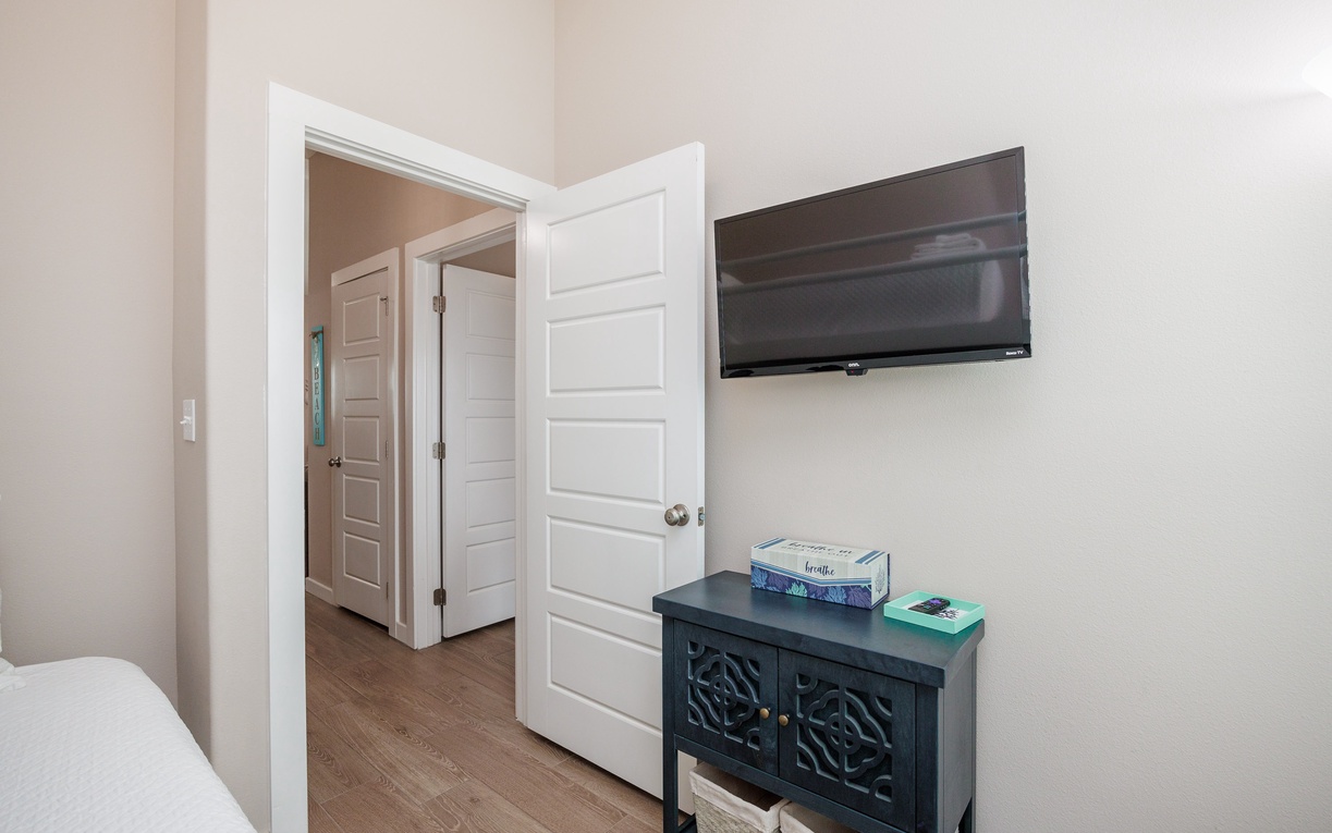 Your spacious bedroom features a wall-mounted TV for cozy nights in, with elegant storage and easy access to adjoining rooms.