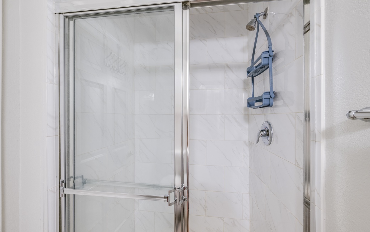 Step into your pristine marble shower with convenient built-in storage and sleek glass doors for a refreshing start to each day.