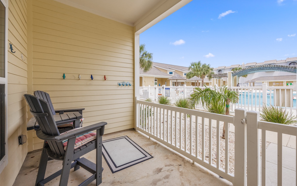 Your private balcony offers a peaceful retreat with comfortable seating overlooking the tropical pool area and lush palms.