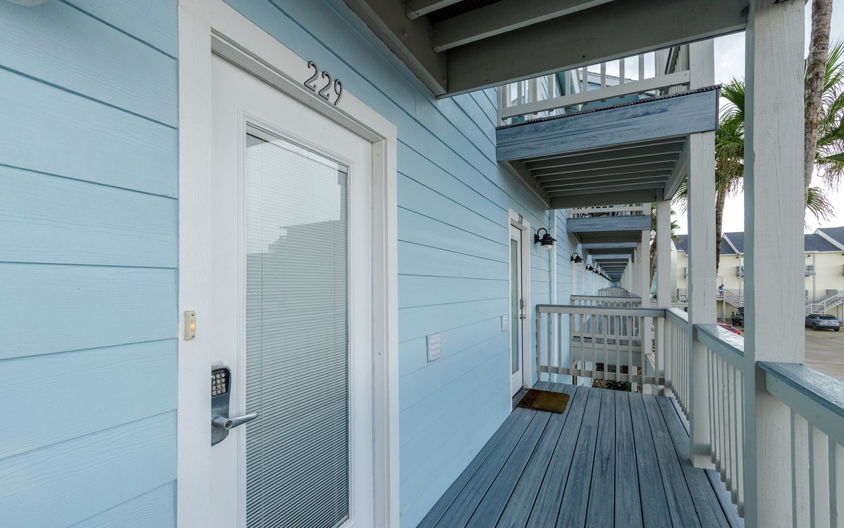 Charming coastal entrance with covered walkway leads to your beachside retreat, complete with keypad entry for convenience.
