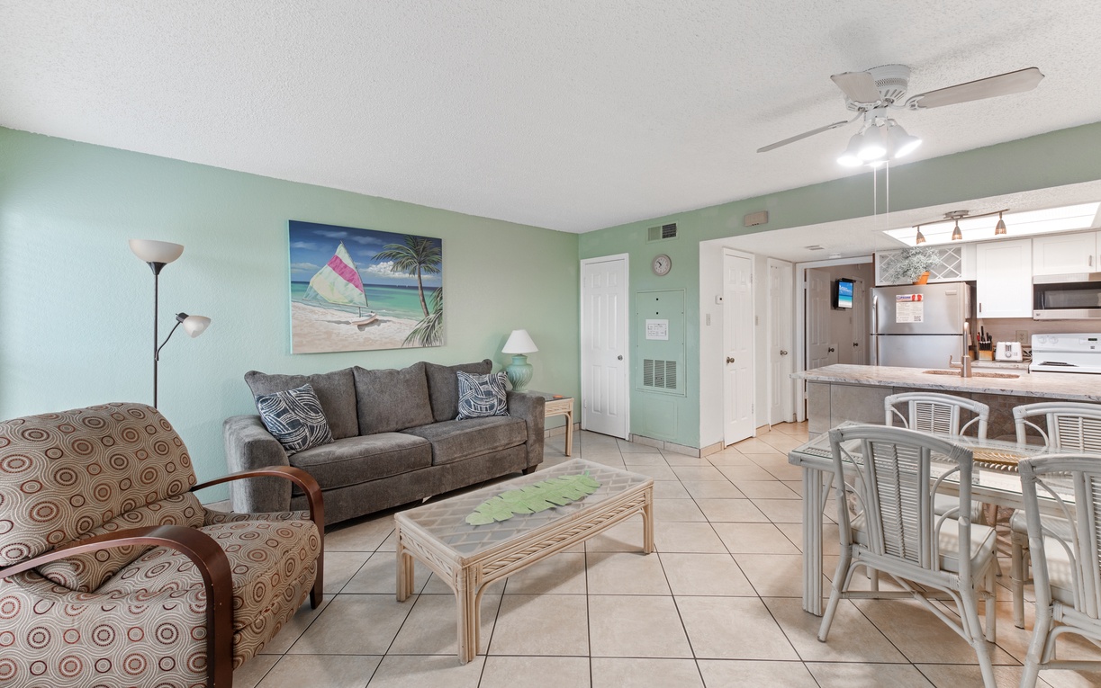 Relax in your coastal-themed living space with comfy seating and open kitchen, perfect for unwinding after beach adventures.