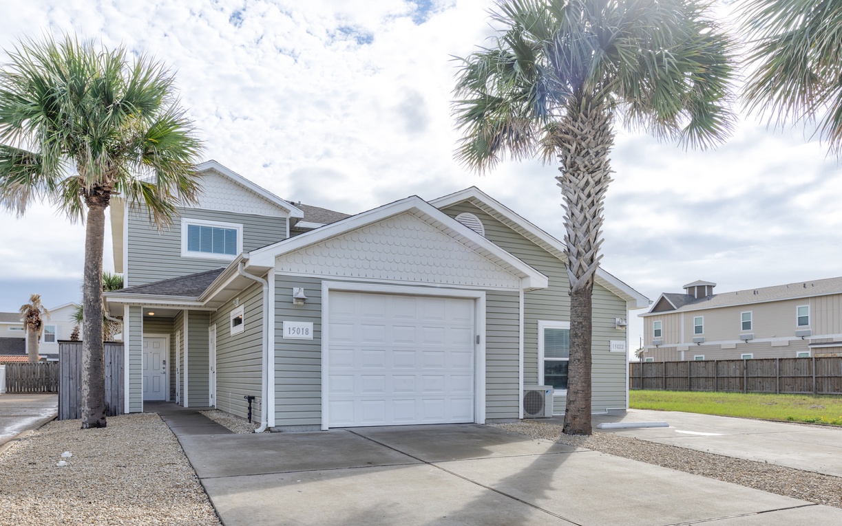 Modern coastal home with convenient garage parking and tropical palm landscaping in a quiet residential neighborhood.