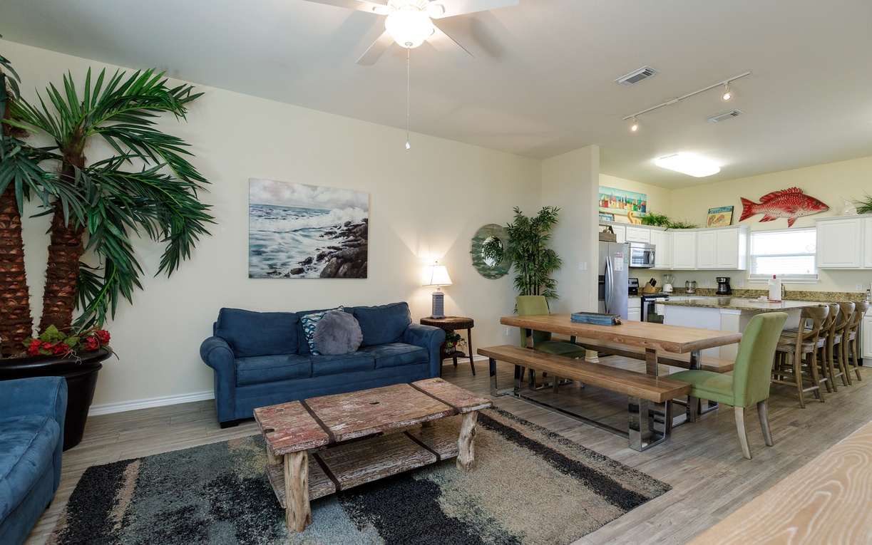 Relax in your bright open living space featuring coastal décor, comfy seating, and a fully-equipped kitchen perfect for memorable meals.