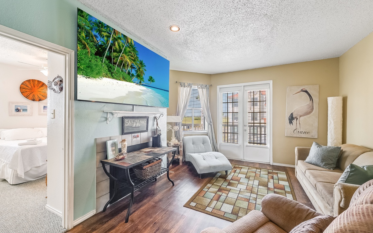 Your spacious living room features coastal artwork, comfortable seating, and French doors opening to your private balcony with stunning views.