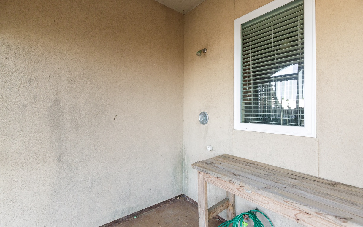 Your private covered patio offers a peaceful retreat with rustic wooden seating and outdoor shower access for refreshing moments.
