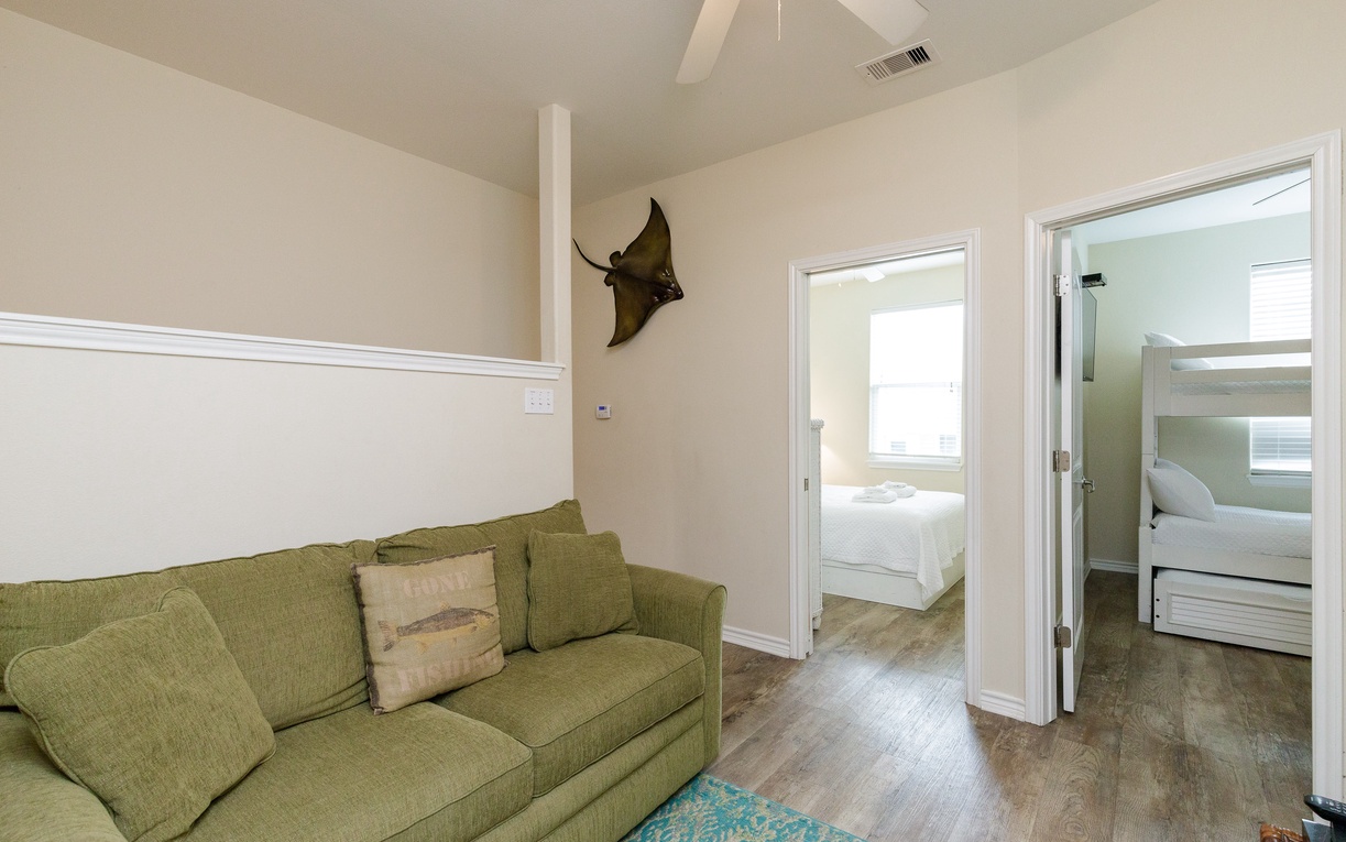 Unwind in your spacious living area with plush olive seating, connecting you to peaceful bedrooms through elegant archways.