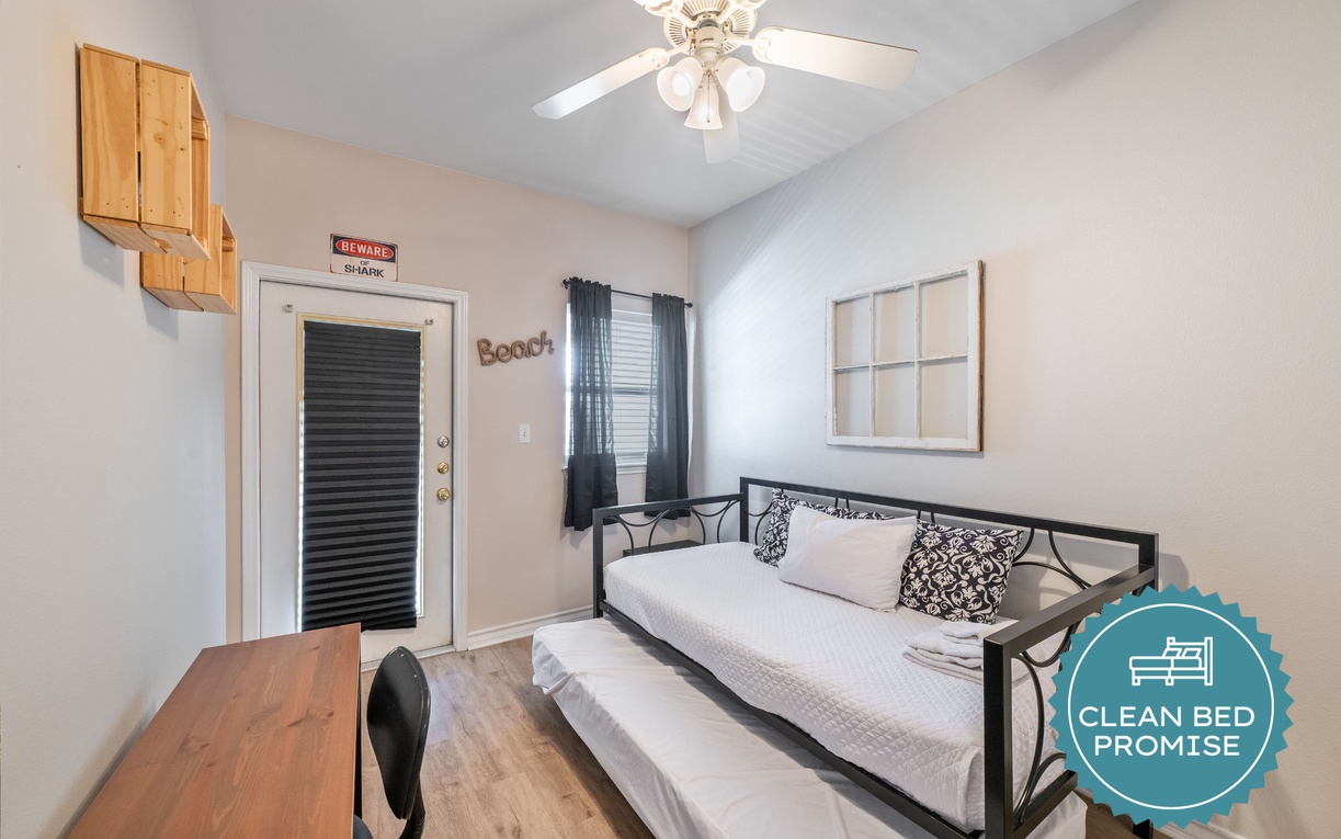 Relax in your cozy bedroom with coastal charm, featuring a comfortable daybed, beach-themed décor, and ceiling fan for perfect comfort.