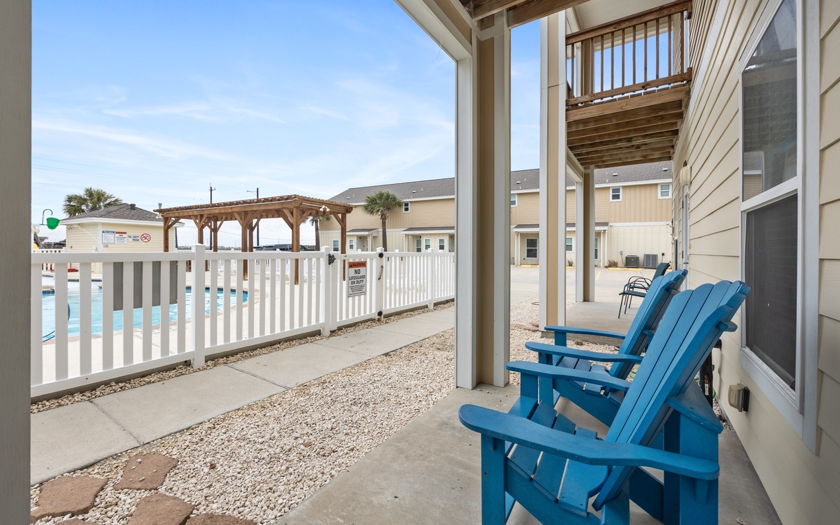 Step onto your private patio and sink into bright blue Adirondack chairs, perfect for morning coffee or sunset relaxation with pool views.