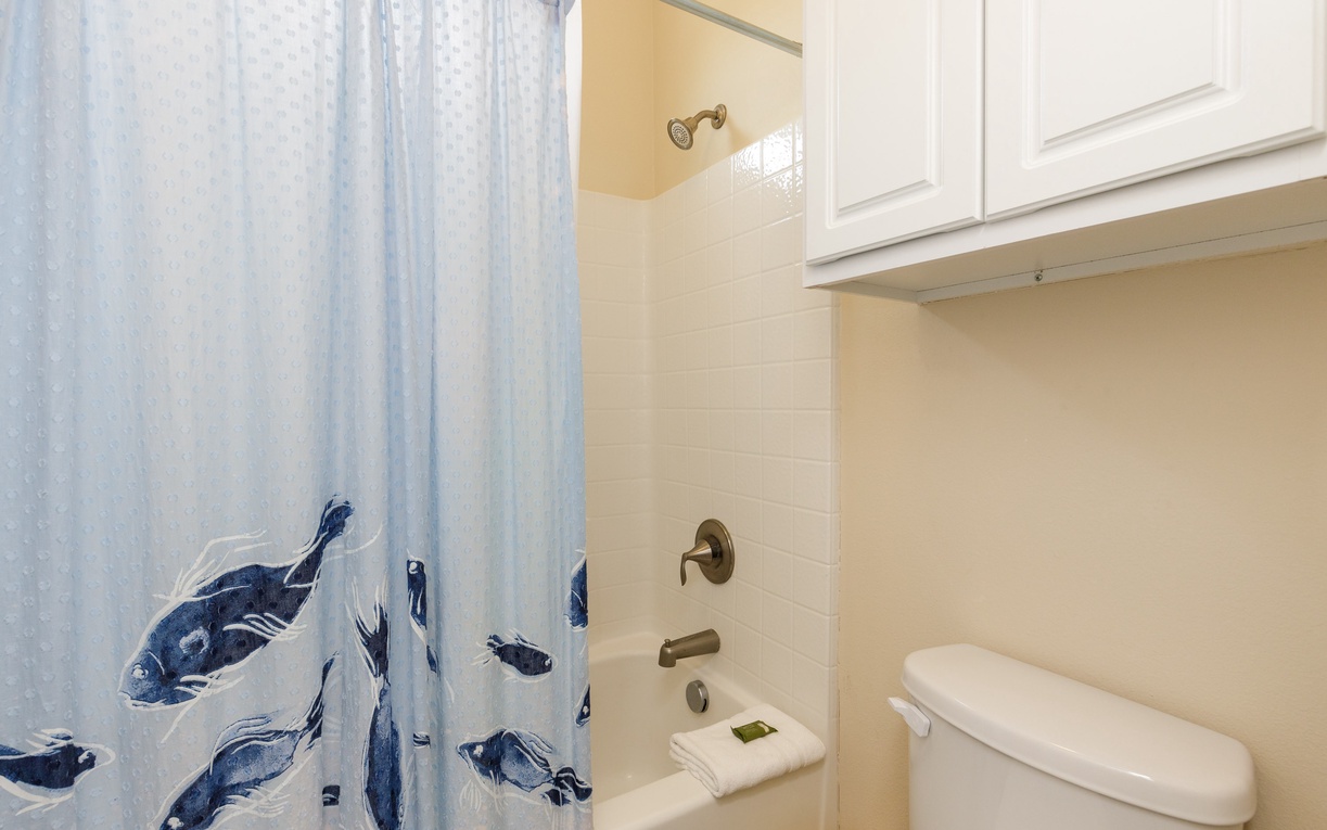 Refresh in your private bathroom with a charming ocean-themed shower curtain and ample storage above.