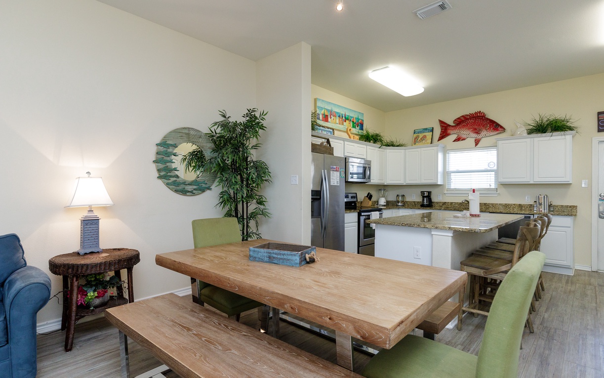 Your open-concept dining area flows into a fully-equipped kitchen, perfect for family meals and coastal-themed relaxation.
