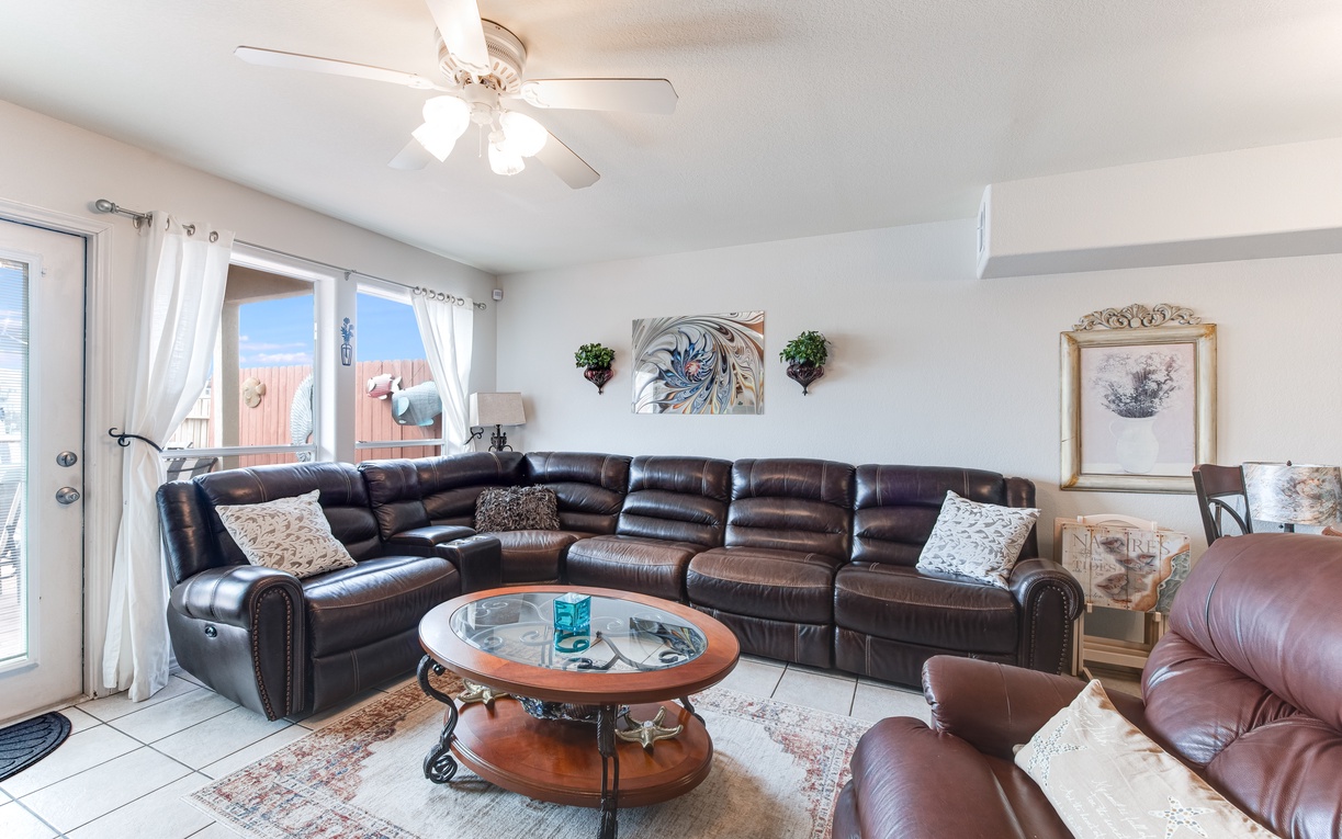 Relax in your spacious living room featuring plush leather seating and natural light from patio doors.