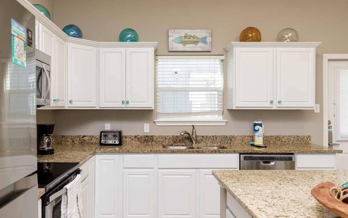 Your fully equipped kitchen features granite countertops, stainless steel appliances, and charming coastal decor - perfect for preparing memorable meals.