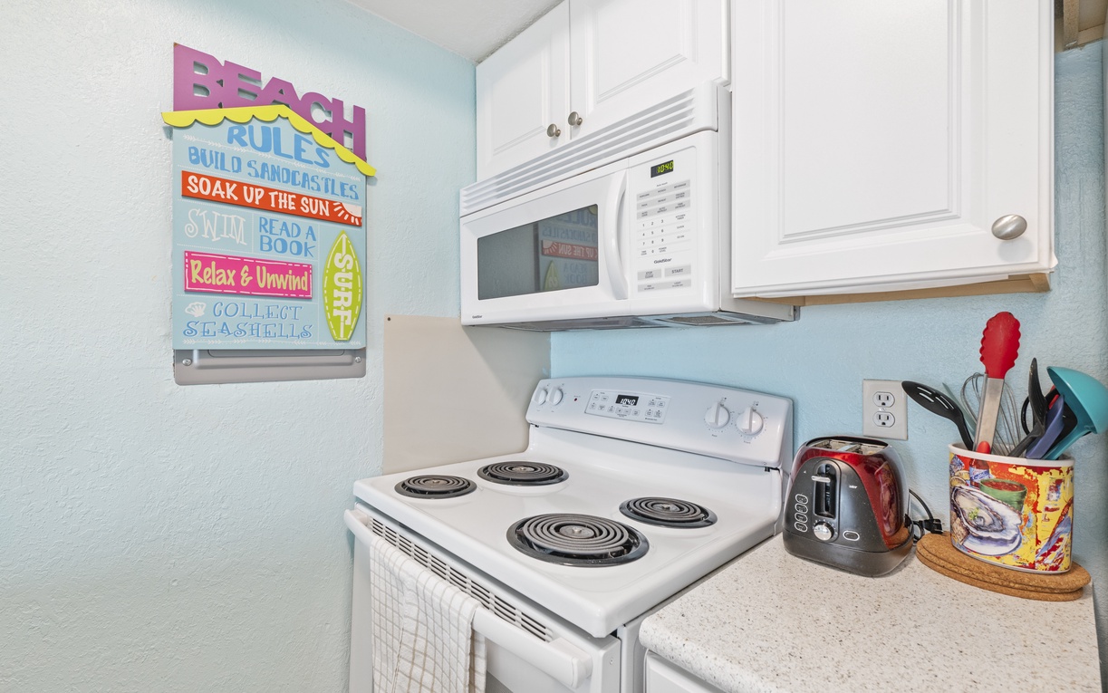 Your fully equipped kitchen awaits with everything you need—stove, microwave, and charming beach-themed touches that set the perfect vacation mood.