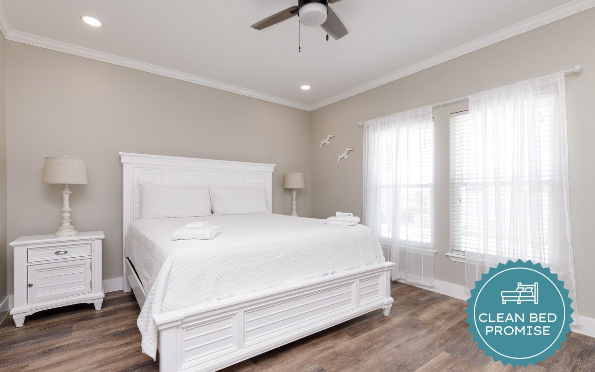 Sink into crisp white linens in this serene bedroom where soft coastal colors and gentle ceiling fan breezes create your peaceful retreat.