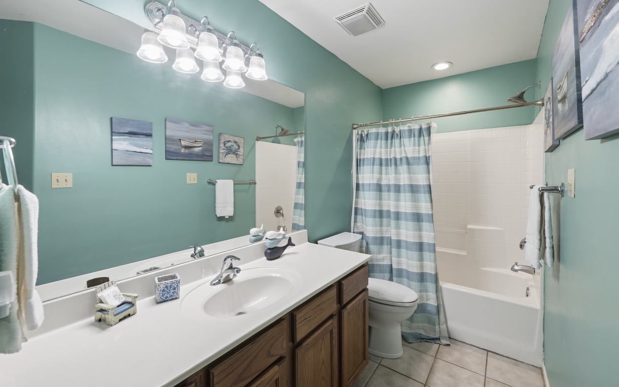Refresh in your coastal-inspired bathroom with soft aqua walls, ample vanity space, and a full tub-shower combo—perfect for unwinding after beach adventures.