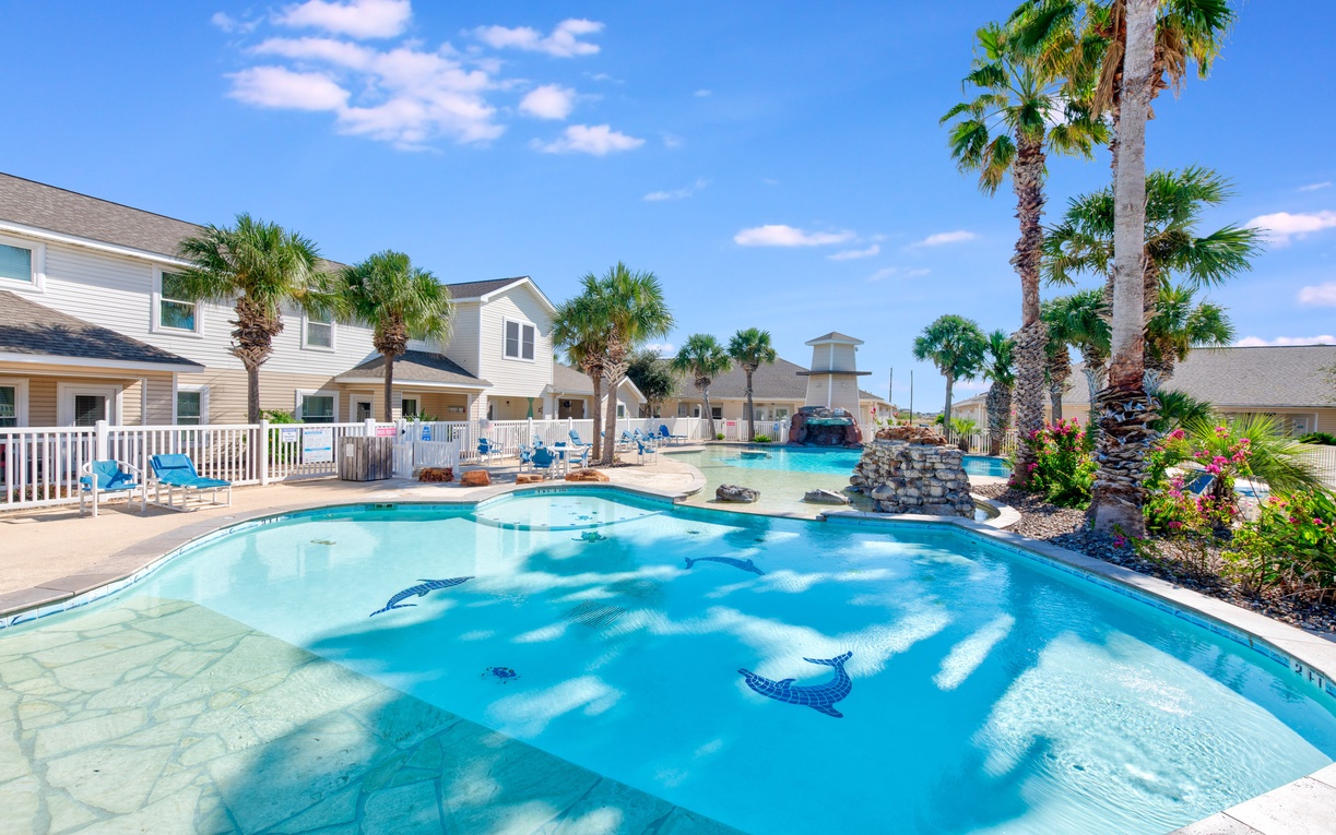 Beautiful resort-style pool area featuring tropical landscaping with palm trees and decorative water features in a peaceful residential setting.