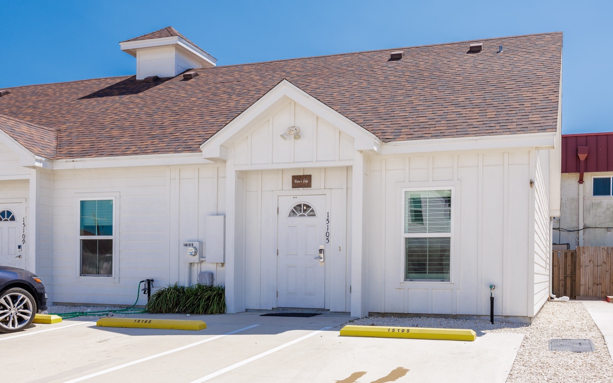 Modern coastal cottage featuring clean white siding and charming architectural details with convenient parking spaces right at your doorstep.