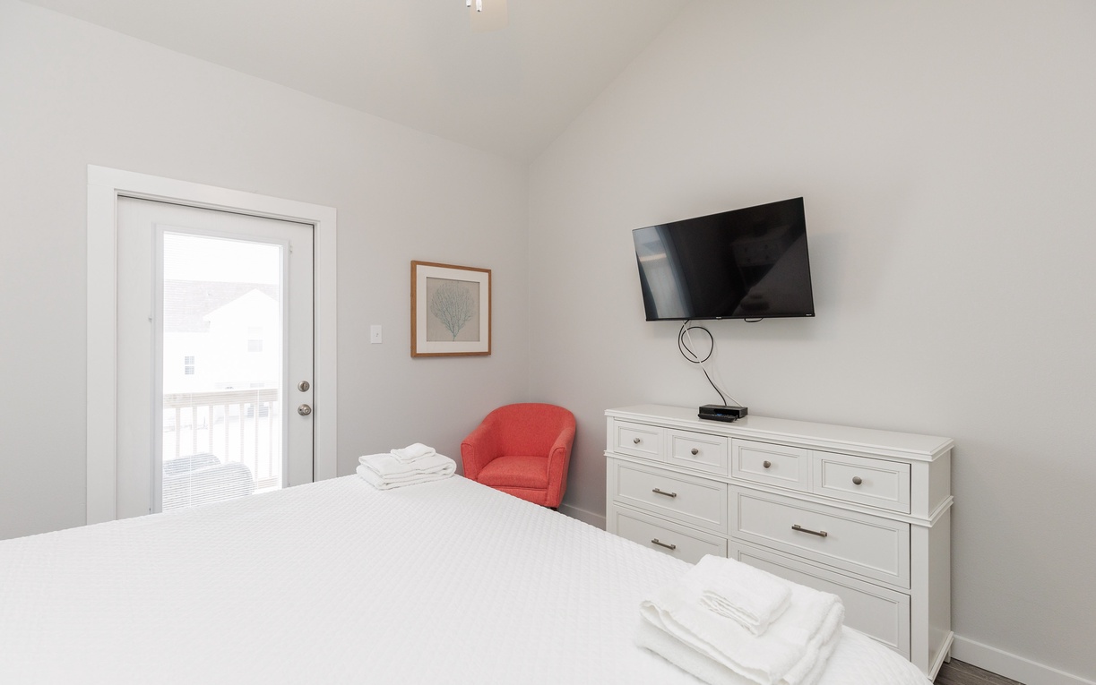 Rest peacefully in your second floor bedroom featuring a king size bed, wall-mounted TV, and fresh linens awaiting your arrival.