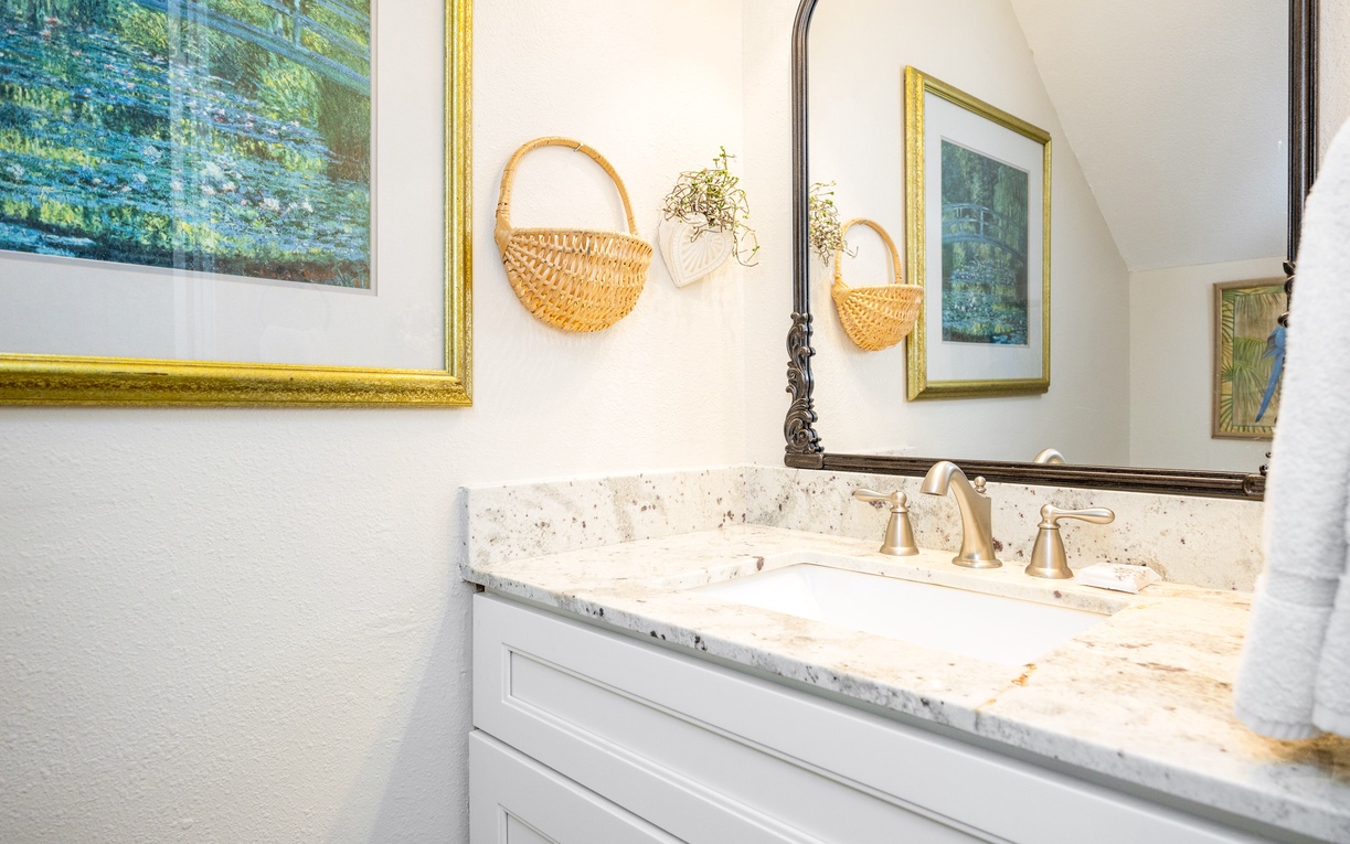 Your elegant first floor half bathroom features marble countertops, brass fixtures, and charming coastal artwork for a sophisticated morning routine.