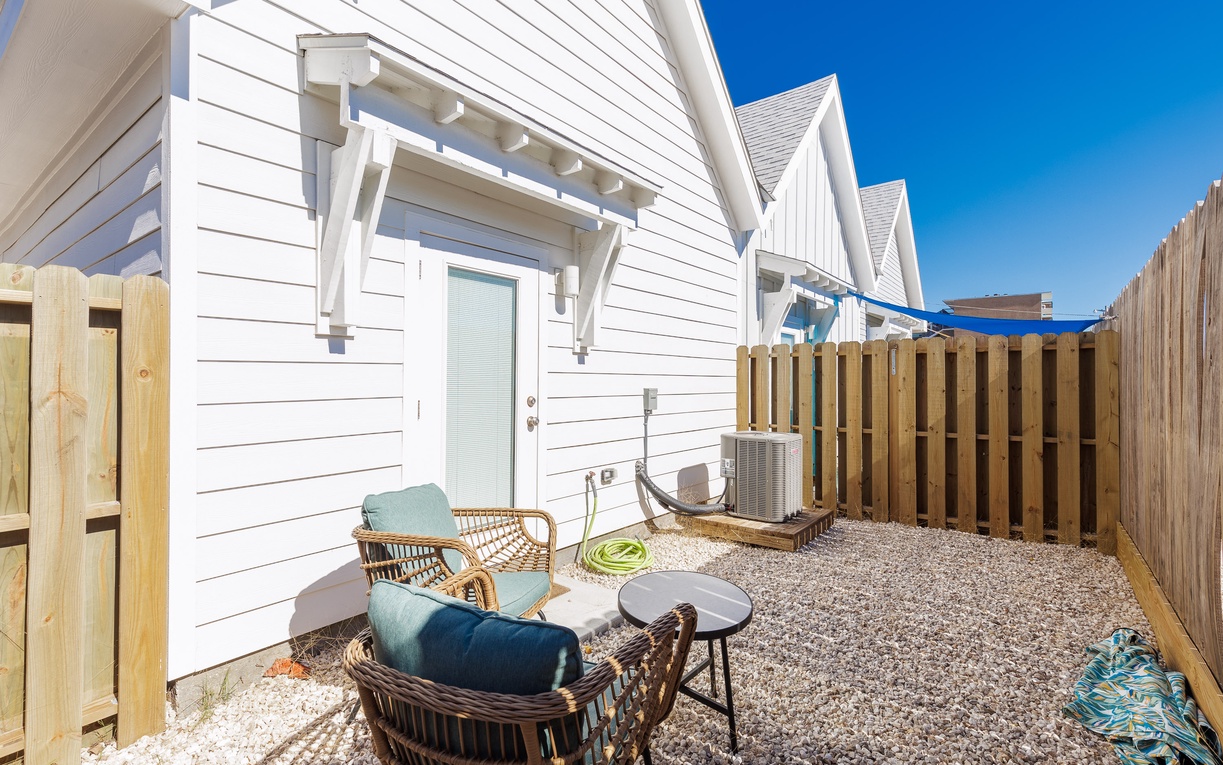 Your private patio offers cozy seating with stylish chairs and table, perfect for morning coffee or evening relaxation under the clear blue sky.