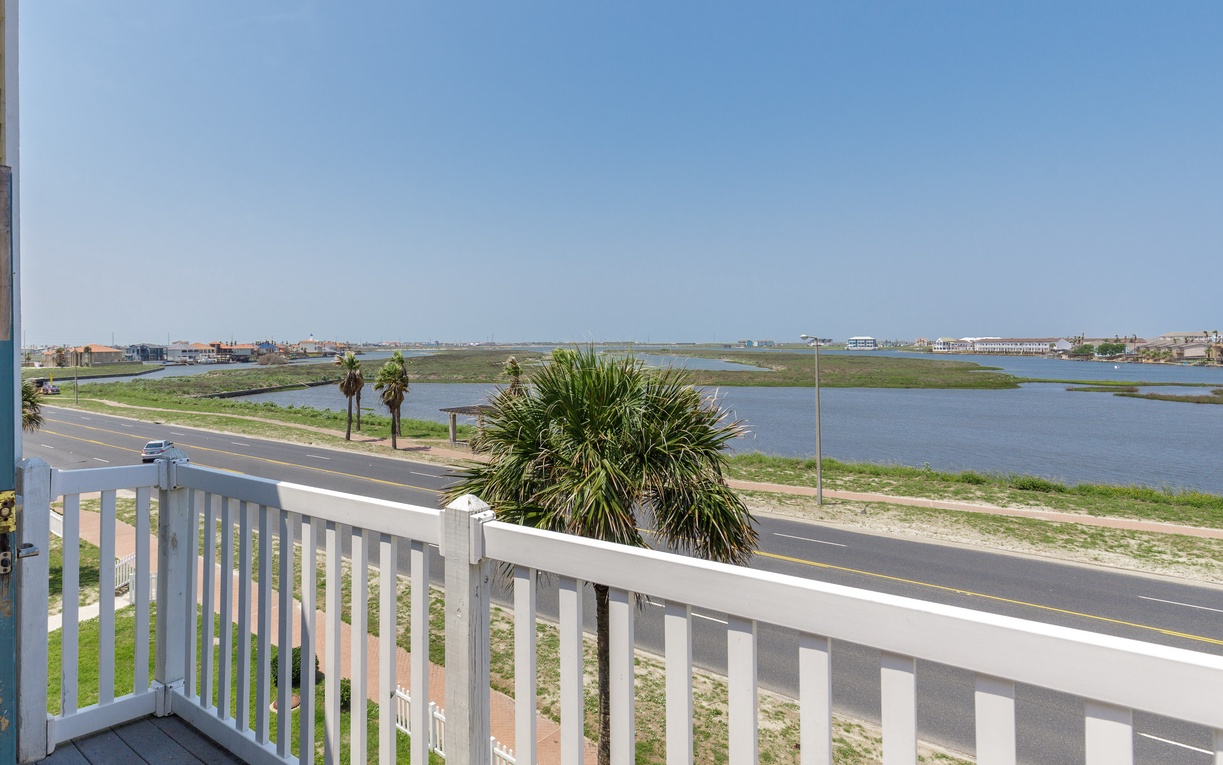 Panoramic waterfront views stretch across peaceful lagoons from this elevated balcony perch overlooking coastal roads and distant shoreline.