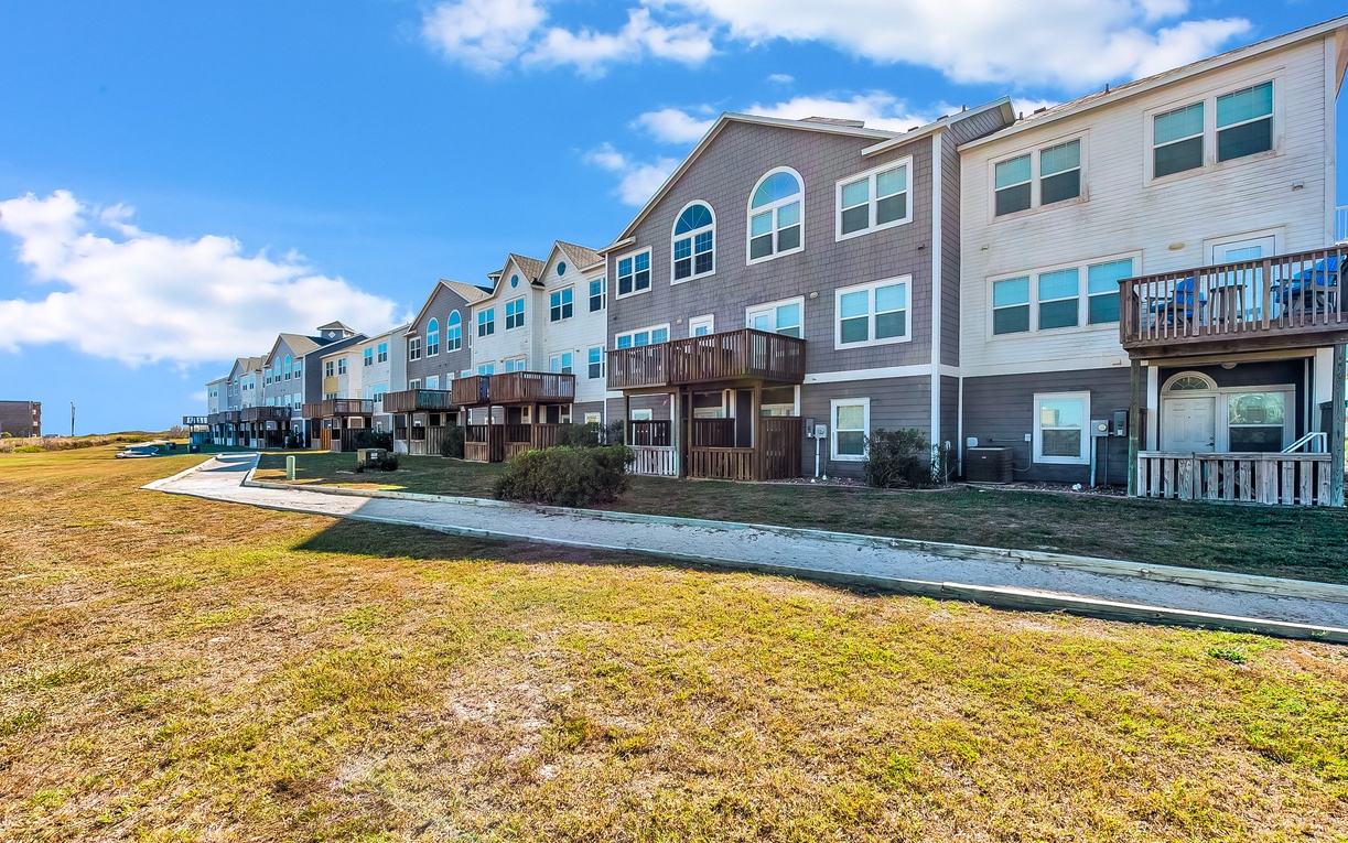 Modern townhome complex featuring contemporary coastal architecture with private balconies in a peaceful neighborhood setting.