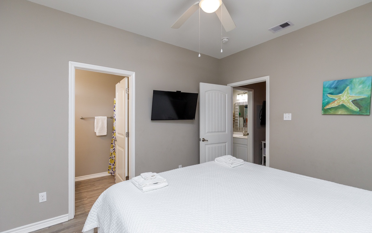 Relax in your private bedroom featuring a comfortable bed, ceiling fan, and flat-screen TV for entertainment.