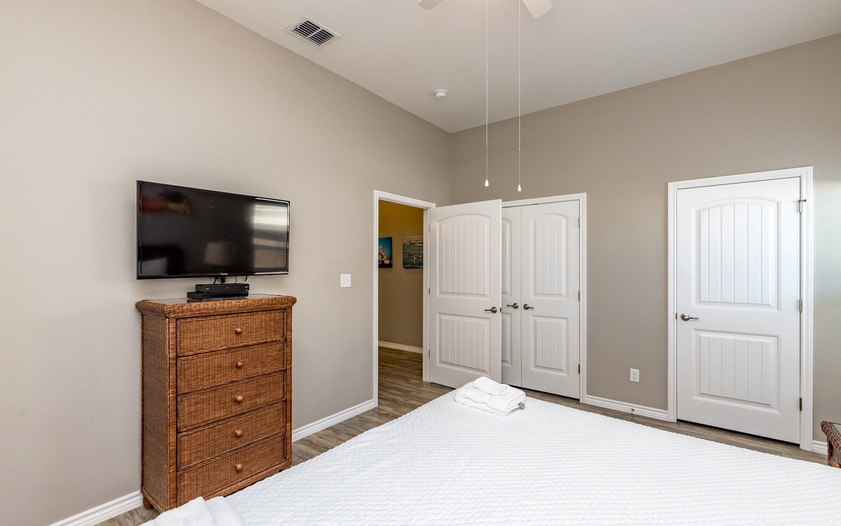 Rest comfortably in your serene bedroom featuring a plush bed, wicker dresser, and flat-screen TV for peaceful evenings.