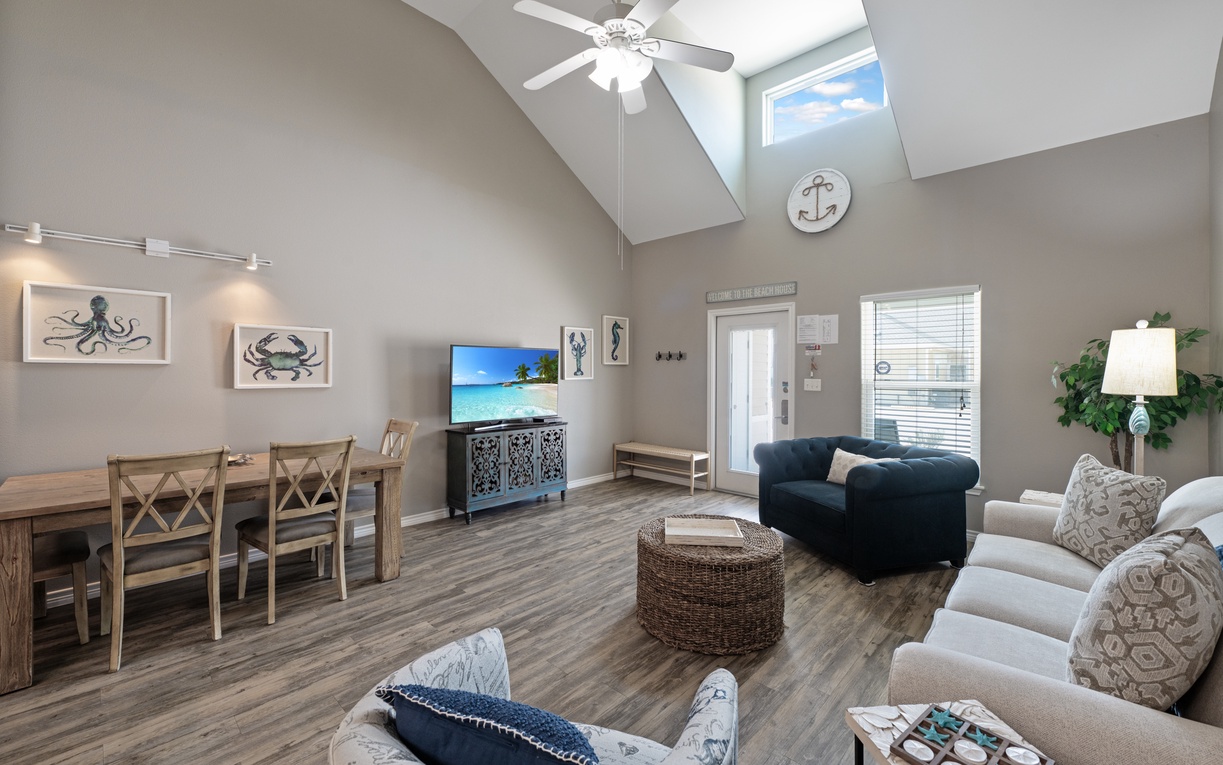 Relax in your coastal-themed living space with vaulted ceilings, nautical art, and comfortable seating perfect for unwinding after beach adventures.