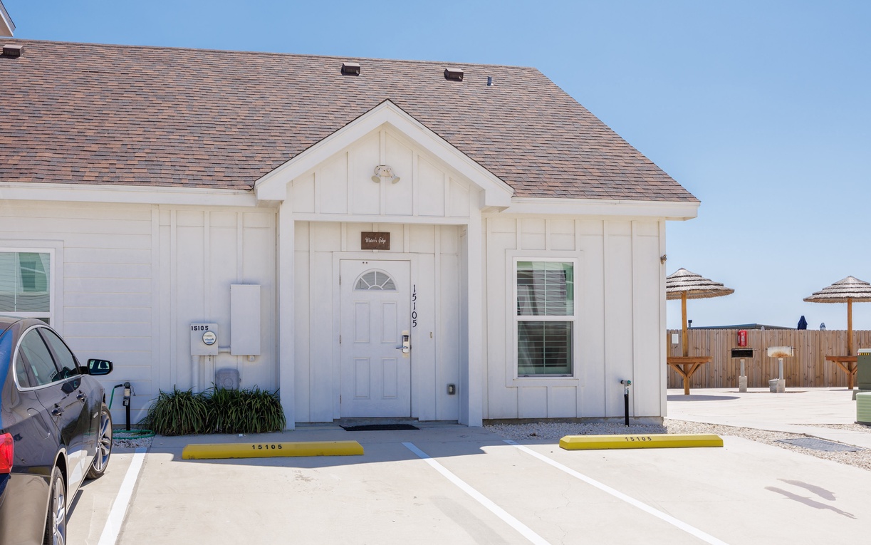 Charming white cottage-style property with convenient parking and modern amenities, perfectly positioned for your coastal getaway.