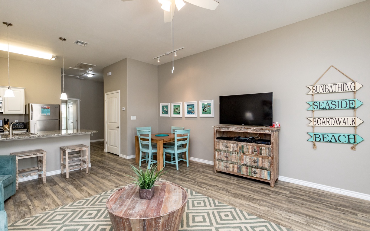 Relax in this bright living area with beach-themed decor, modern kitchen, and coastal charm for your perfect getaway.