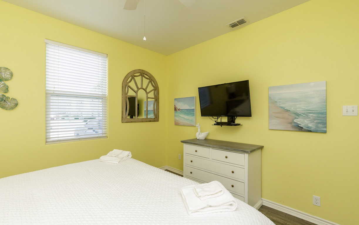 Wake up in your sunny yellow bedroom with crisp linens, ocean artwork, and a flat-screen TV for relaxing evenings.