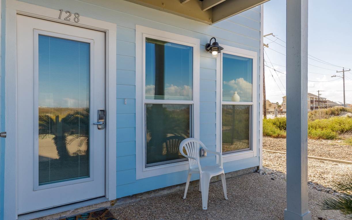 Coastal cottage entry with covered porch and ocean glimpses through windows, perfect for peaceful beach getaways.