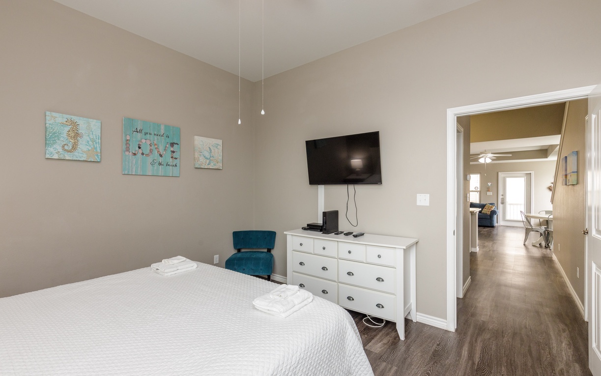 Unwind in your cozy bedroom with a plush bed, wall-mounted TV for evening entertainment, and ample storage in the white dresser.