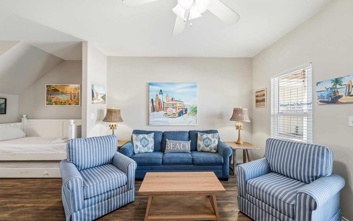 Sink into plush seating in your bright, breezy living space, where coastal charm meets comfort with vaulted ceilings and cheerful blue accents welcoming you home.