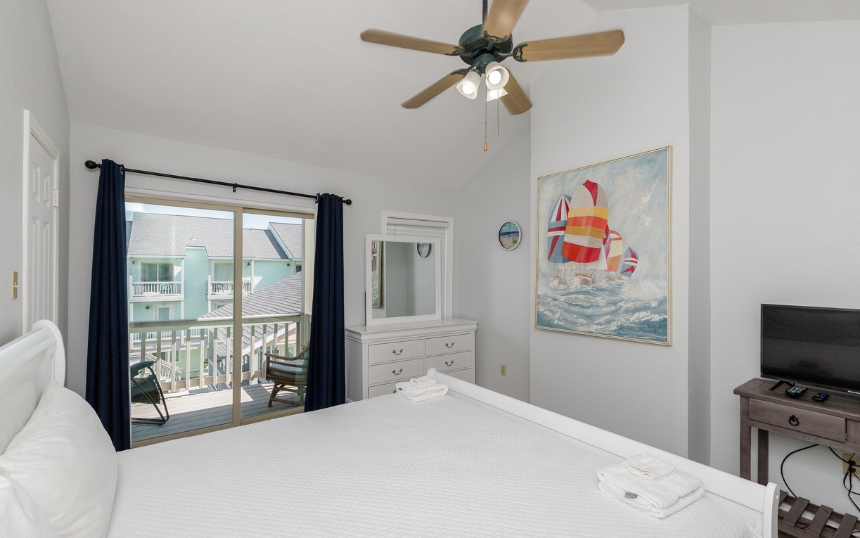 Your coastal bedroom features crisp white linens, nautical art, and a private balcony overlooking charming neighborhood rooftops.