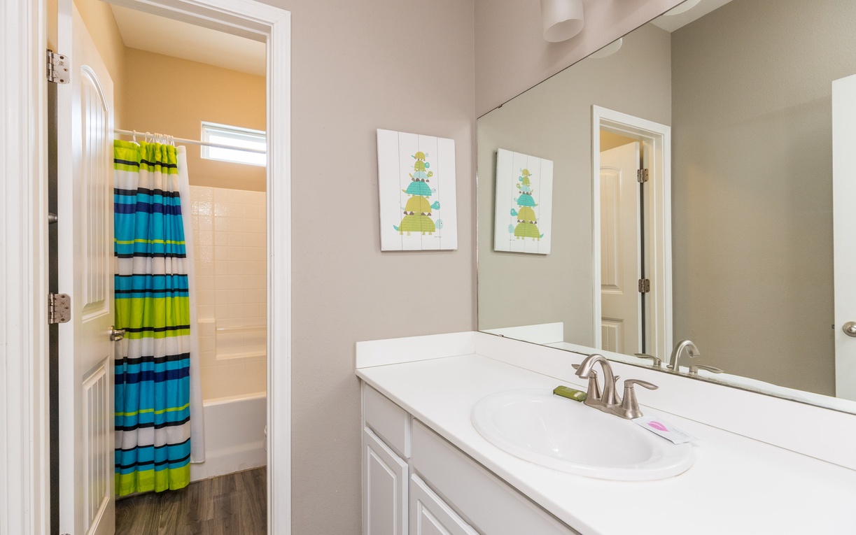Your bright bathroom features a marble-topped vanity and cheerful striped shower curtain, creating a fresh space for your morning routine.