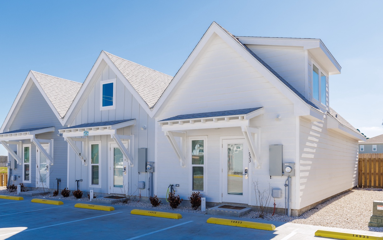 Modern white cottage-style vacation rental with charming architectural details and convenient parking spaces.
