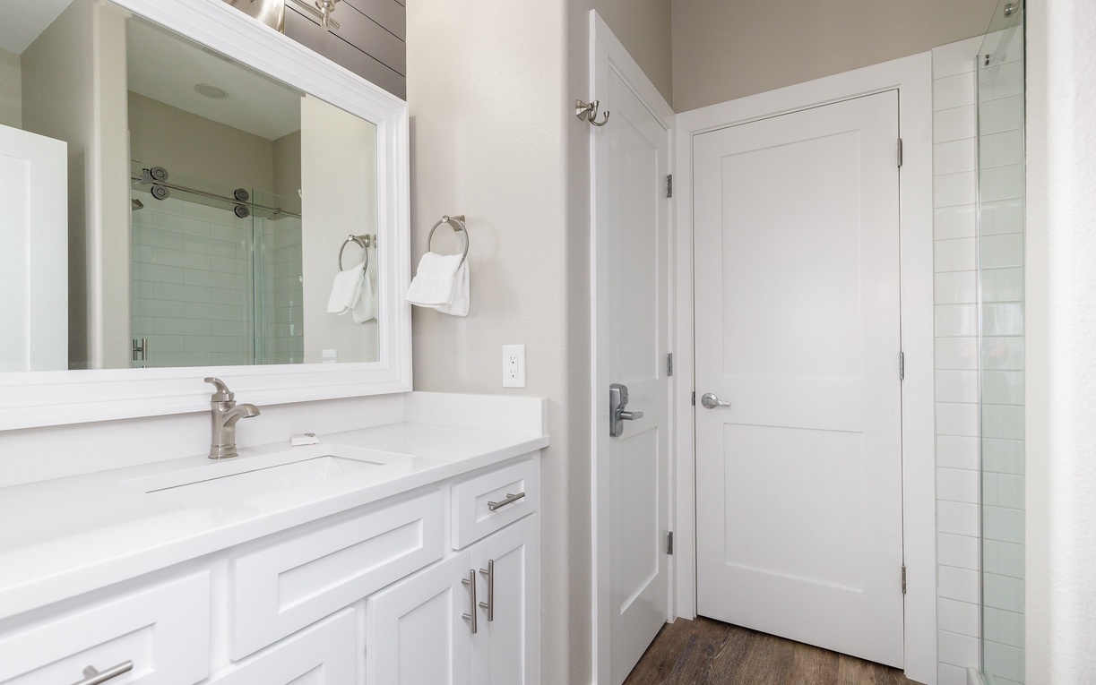 Step into your pristine ensuite featuring gleaming marble countertops, crisp white cabinetry, and a spacious glass shower for your ultimate comfort.