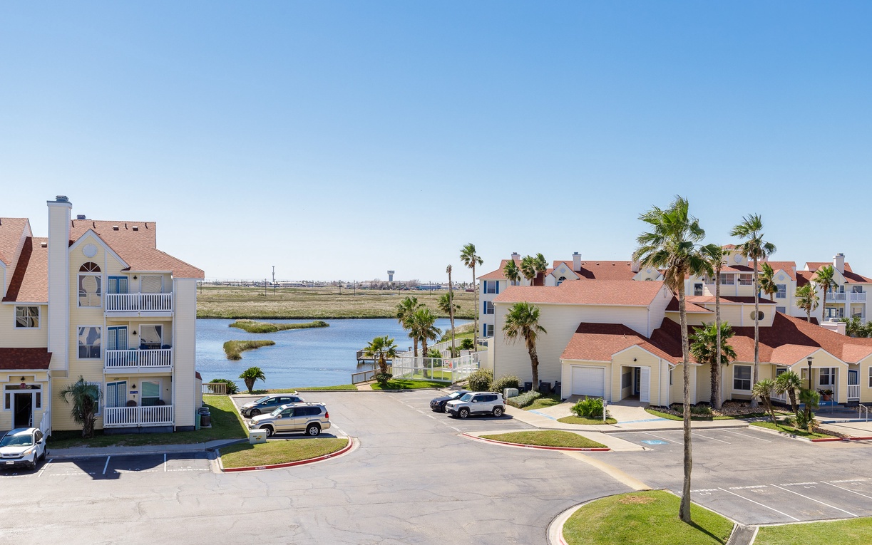 Waterfront resort community featuring palm-lined buildings with scenic views across peaceful lagoons and coastal marshlands.