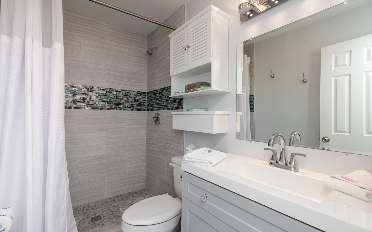 Unwind in your beautifully renovated bathroom featuring modern tile work, elegant fixtures, and thoughtful storage solutions for a refreshing stay.